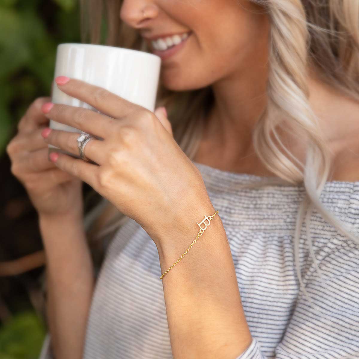 Girl wearing her 14k yellow gold monogram bracelet with a satin finish 