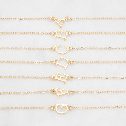 Several 14k yellow gold monogram bracelets with a satin finish going from the letters A to G