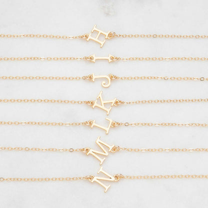 Several 14k yellow gold monogram bracelets with a satin finish going from the letters H to N