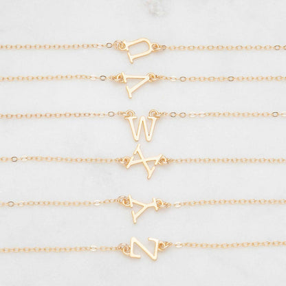 Several 14k yellow gold monogram bracelets with a satin finish going from the letters U to Z