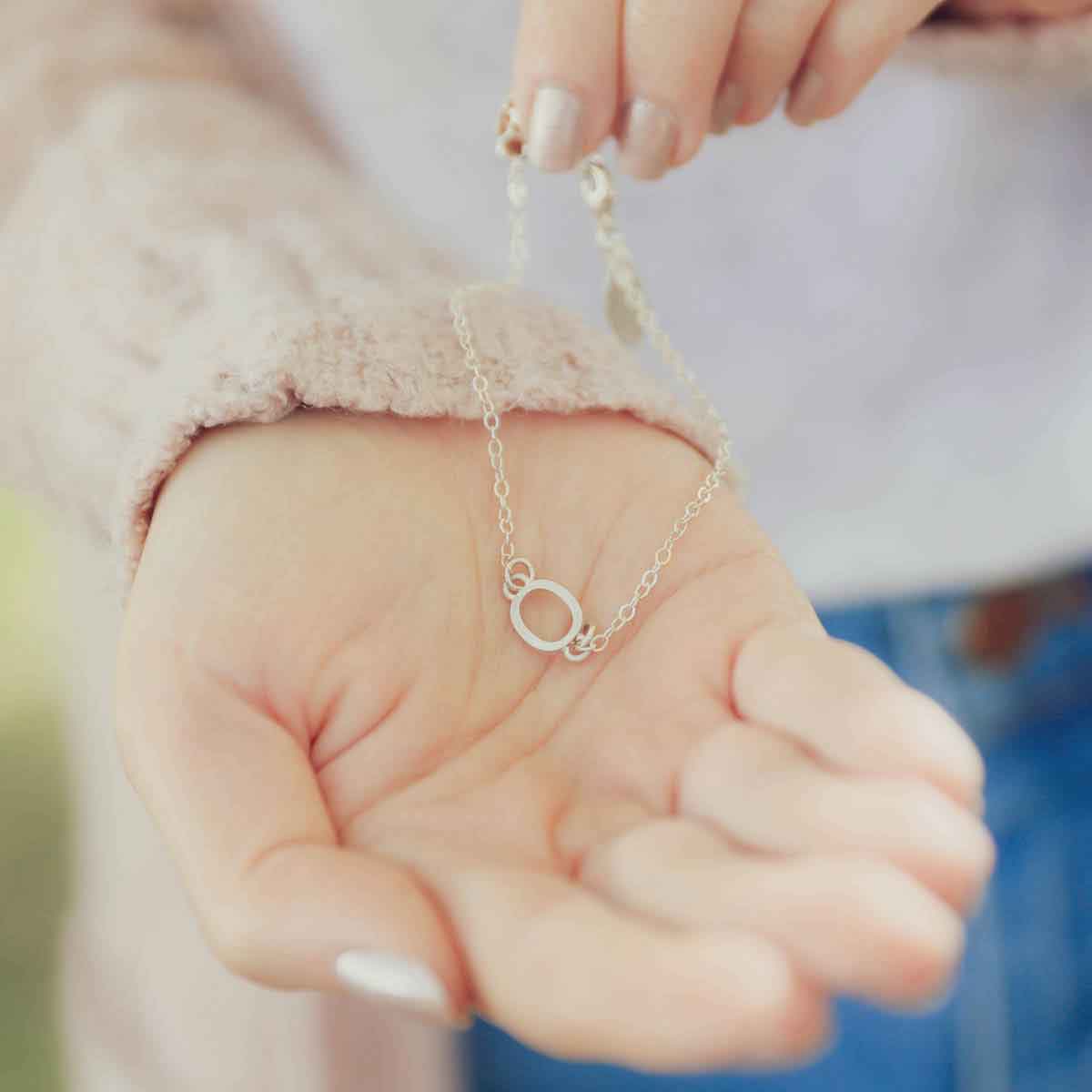 Girl holding a Sterling silver monogram bracelet with a satin finish 