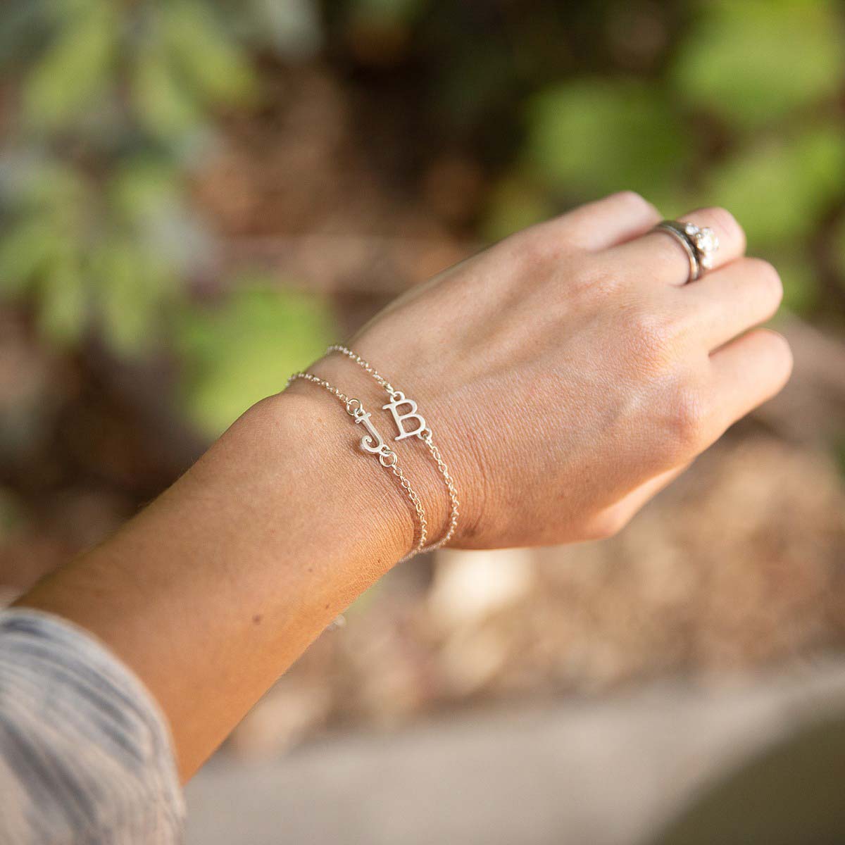 Girl wearing a pair of Sterling silver monogram bracelets with a satin finish 