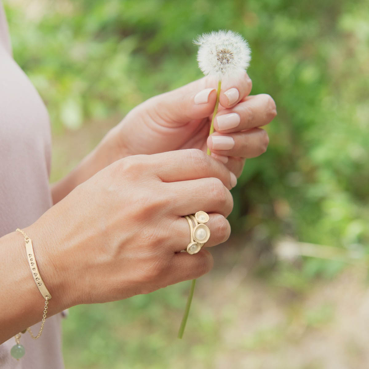 Girl wearing Nesting freshwater large pearl ring hand cast in 14k yellow gold holding inside a large 6mm freshwater pearl with other gold jewelry