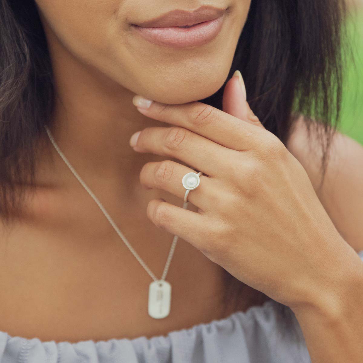 Girl wearing Nesting freshwater large pearl ring hand cast in sterling silver holding inside a large 6mm freshwater pearl along with other sterling silver jewelry