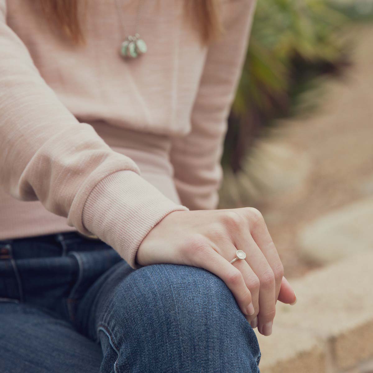 Girl wearing her Nesting freshwater small pearl ring hand cast in sterling silver holding inside a small 4mm freshwater pearl