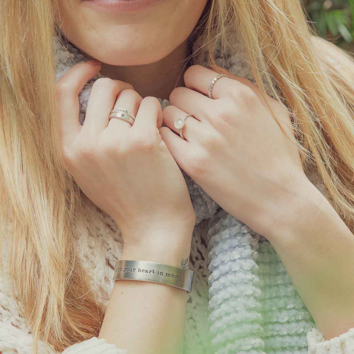 Girl wearing her Nesting freshwater small pearl ring hand cast in sterling silver holding inside a small 4mm freshwater pearl along with other sterling silver and pewter jewelry