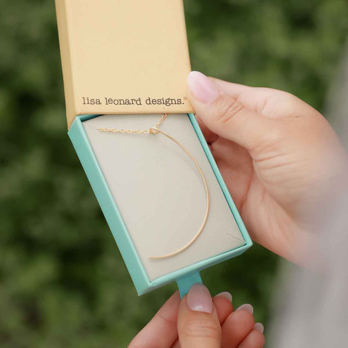 Woman holding a gold filled New Moon Necklace