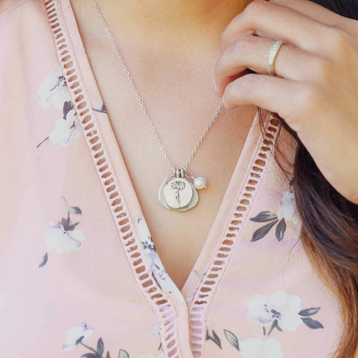 Girl wearing her November birth flower necklace handcrafted in sterling silver with a special birth month charm strung with a vintage freshwater pearl