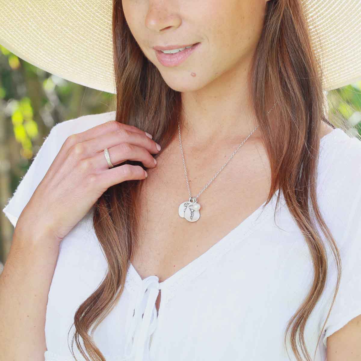 Girl wearing her October birth flower necklace handcrafted in sterling silver with a special birth month charm strung with a vintage freshwater pearl