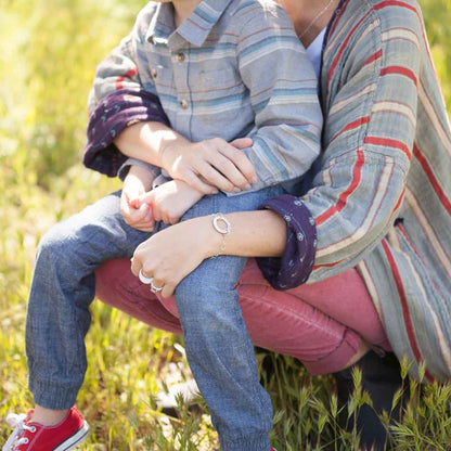 Woman with her son wearing a sterling silver open circle pearl bracelet with a cream freshwater pearl