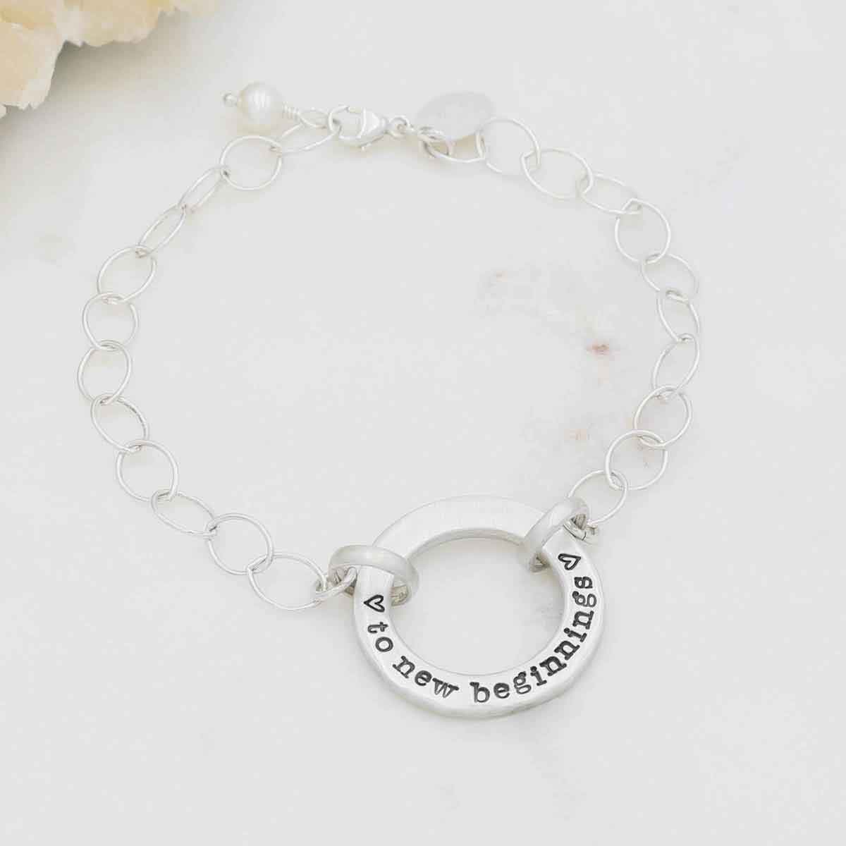 Sterling silver open circle pearl bracelet with a dangling freshwater pearl on marble background