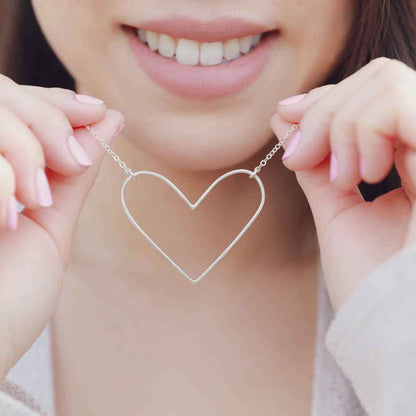 girl holding a Peaceful Heart Necklace handcrafted in sterling silver