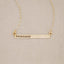 14k yellow gold personalized cross bar necklace customized with name or phrase, on beige background