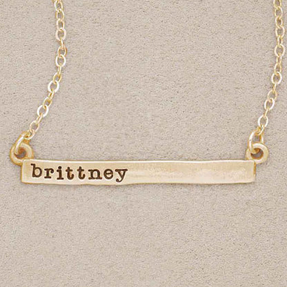  wearing a yellow gold personalized cross bar necklace