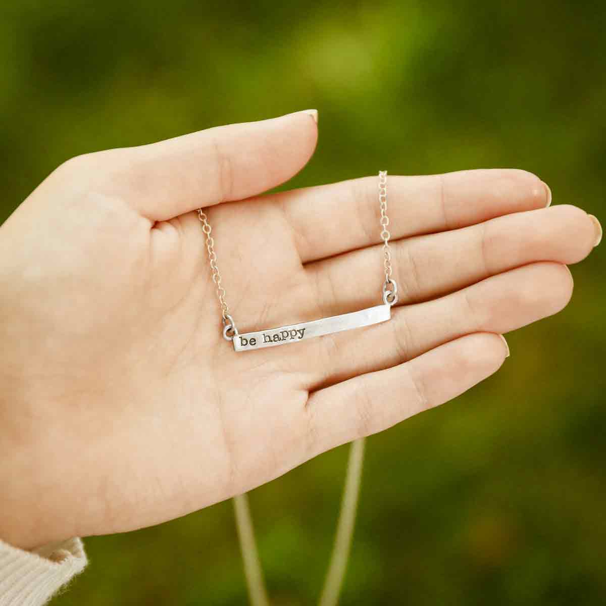 hand holding sterling silver personalized cross bar necklace 