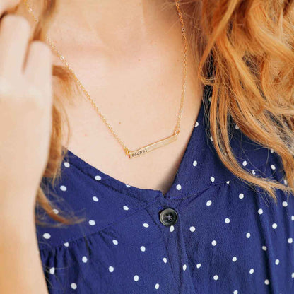 hand holding a yellow gold personalized cross bar necklace