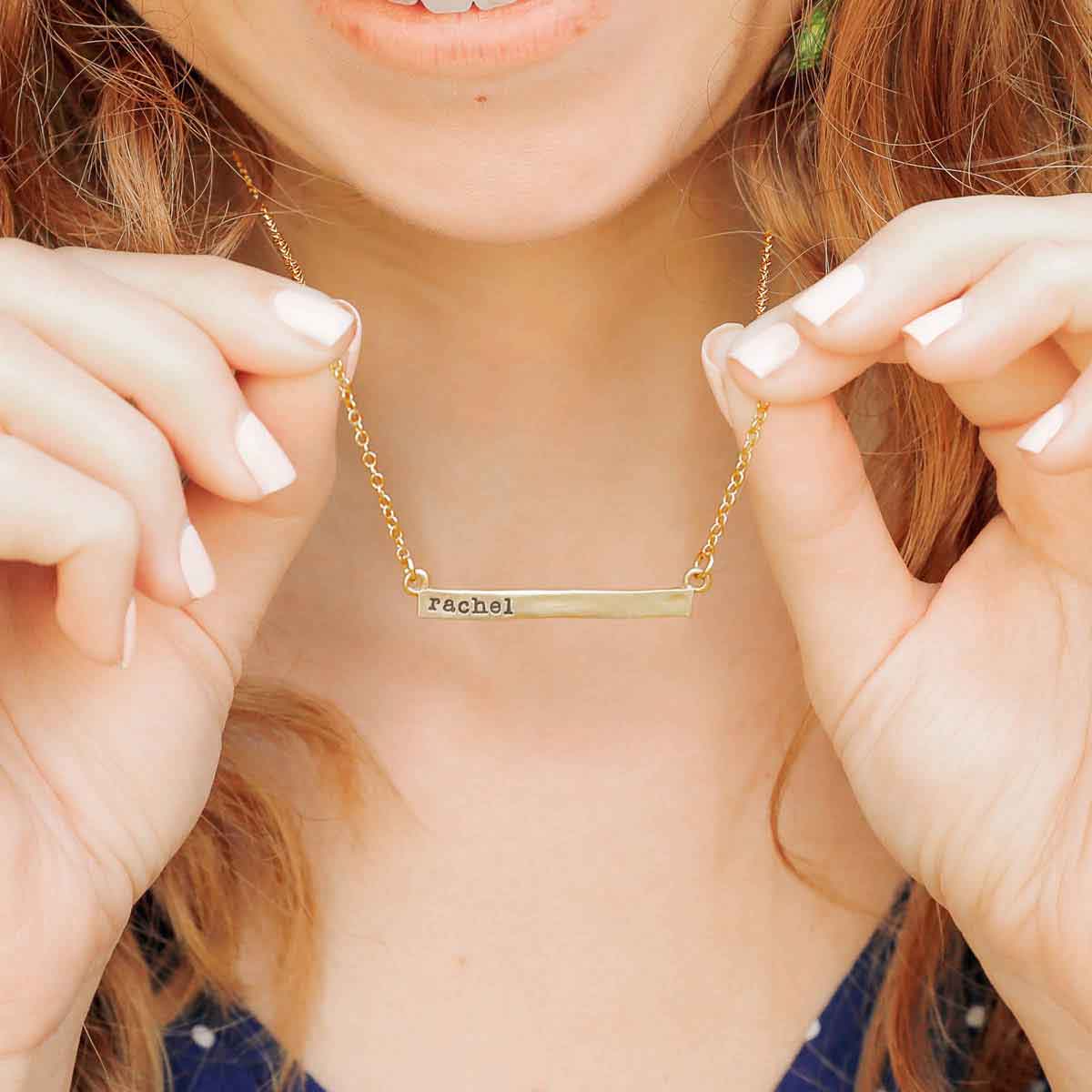  wearing a yellow gold personalized cross bar necklace