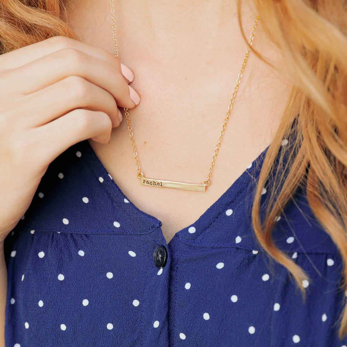  wearing a yellow gold personalized cross bar necklace