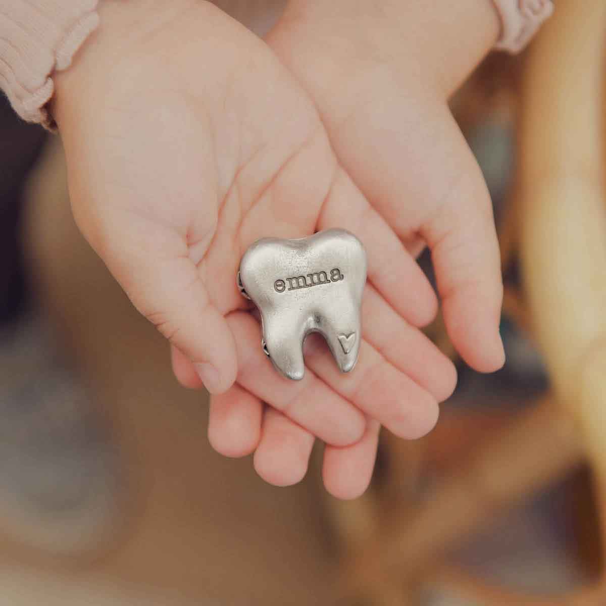 a child holding a Personalized tooth fairy box handcrafted in pewter and hand stamped with their name on it