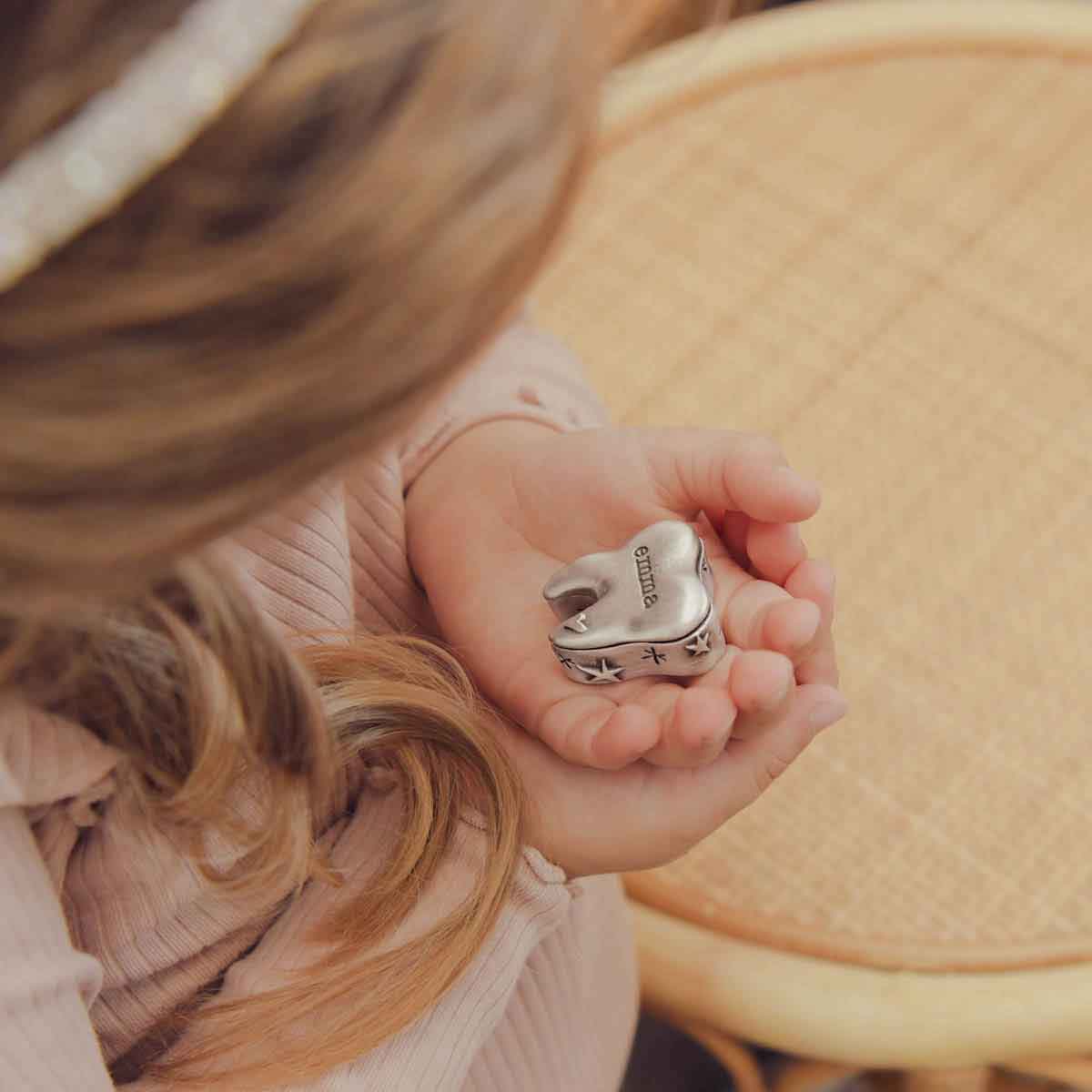 a child holding a Personalized tooth fairy box handcrafted in pewter and hand stamped with their name on it