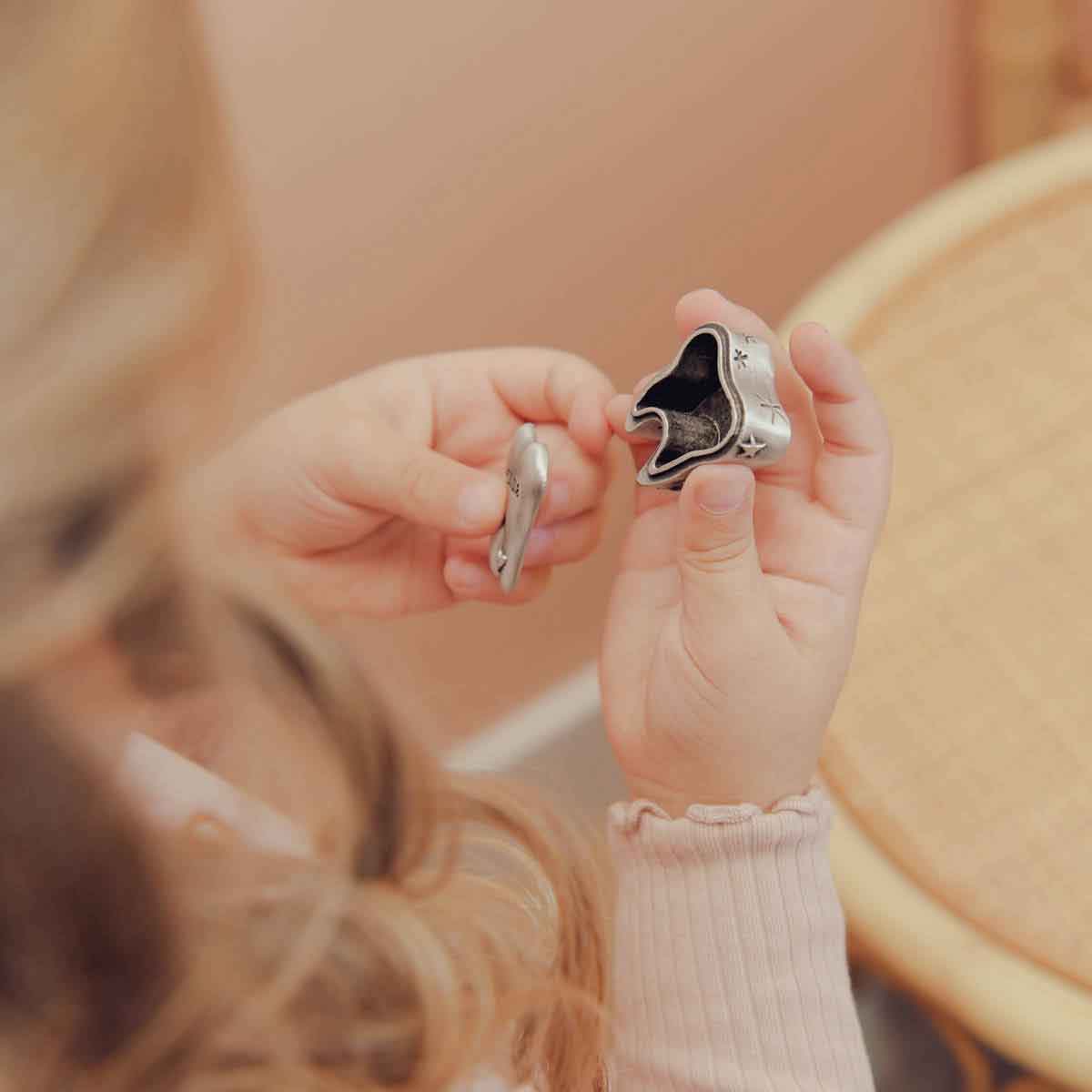 a child holding a Personalized tooth fairy box handcrafted in pewter and hand stamped with their name on it