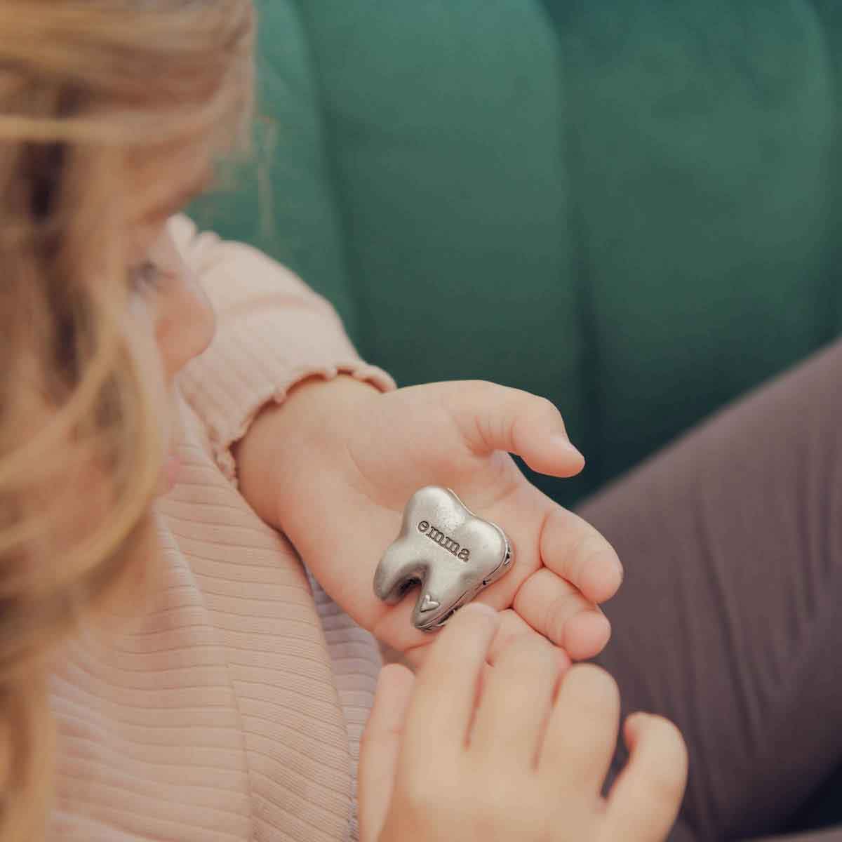 a child holding a Personalized tooth fairy box handcrafted in pewter and hand stamped with their name on it