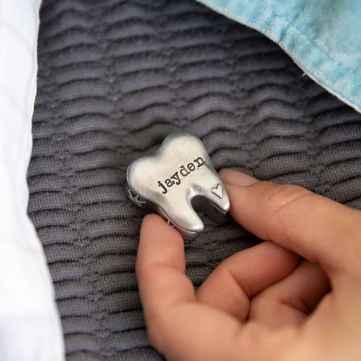 a child holding a Personalized tooth fairy box handcrafted in pewter and hand stamped with their name on it