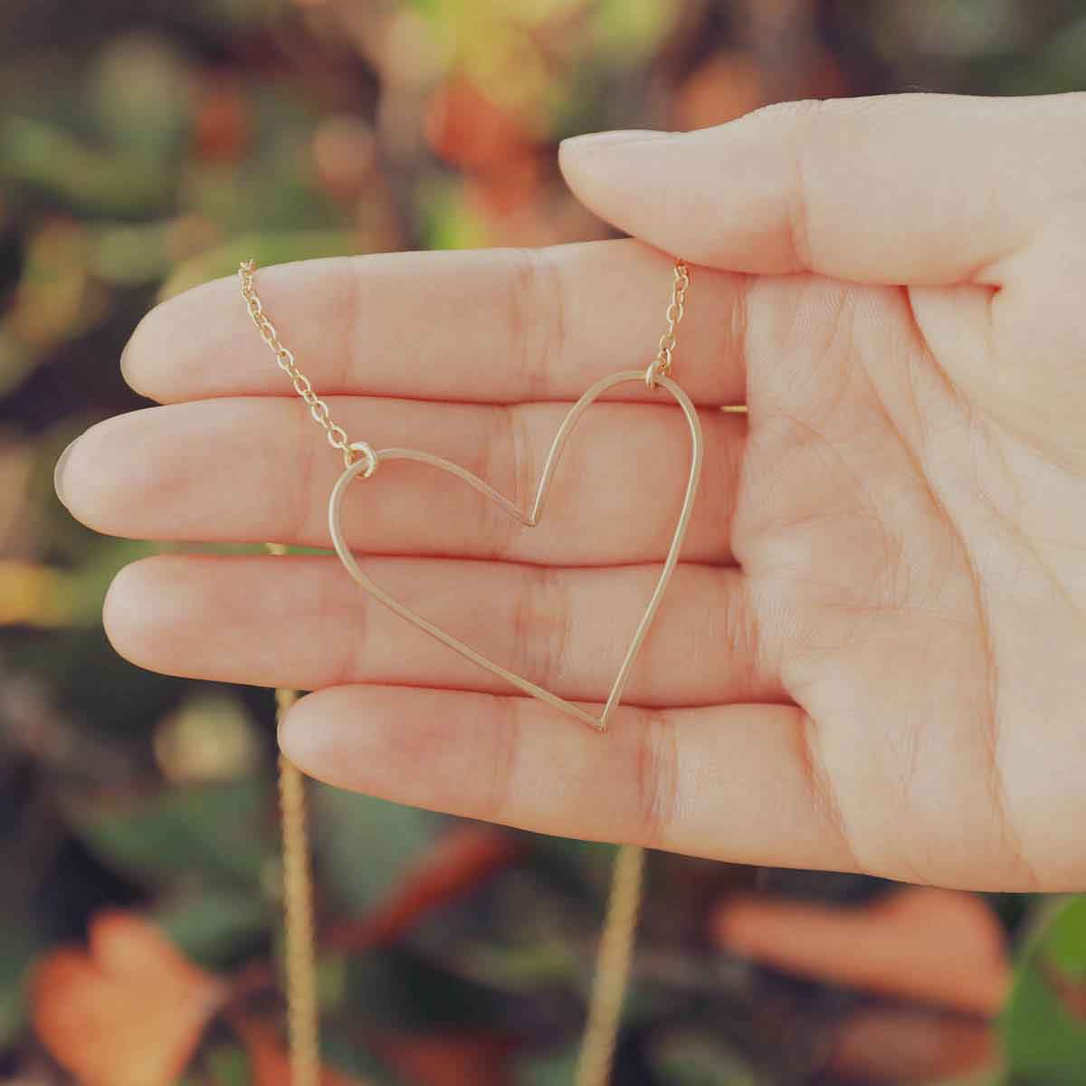 Woman holding a gold filled Petite Peaceful Heart Necklace