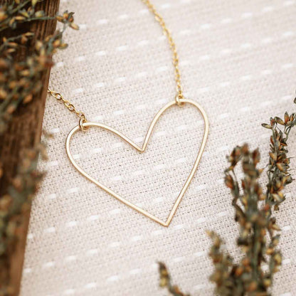 A gold filled Petite Peaceful Heart Necklace on canvas