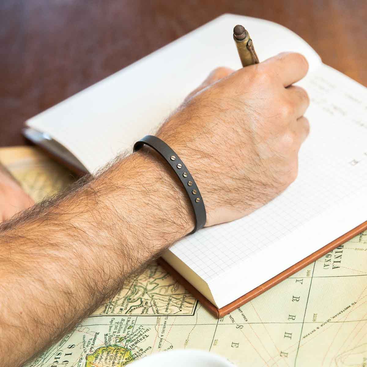 Man wearing Resiliency black cuff bracelet handcrafted in sterling silver and sandblasted to a matte black finish with your choice of up to 6 bronze rivets