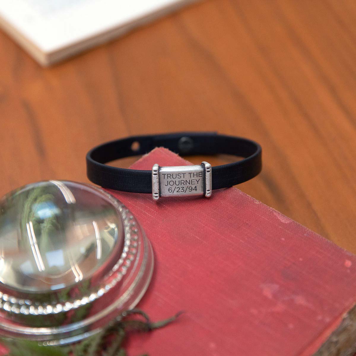 Resolute bracelet handcrafted in black latigo leather with a sterling silver charm and button stud closure and customizable with up to 3 lines