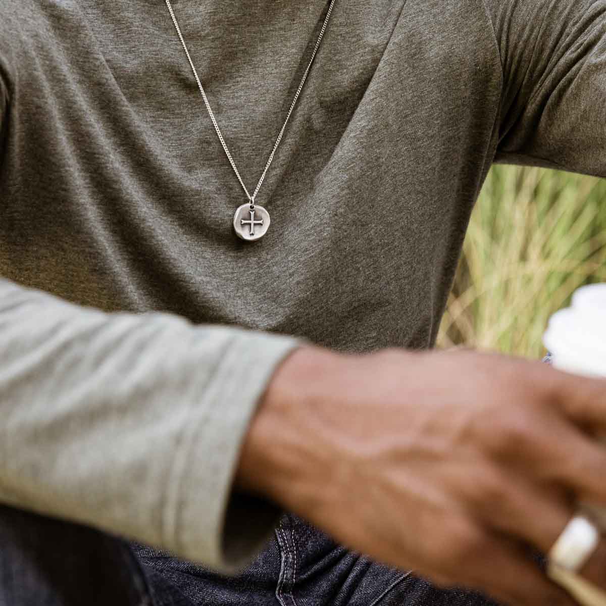 Man wearing Roman Cross Coin necklace handcrafted in sterling silver strung on sterling silver curb chain 