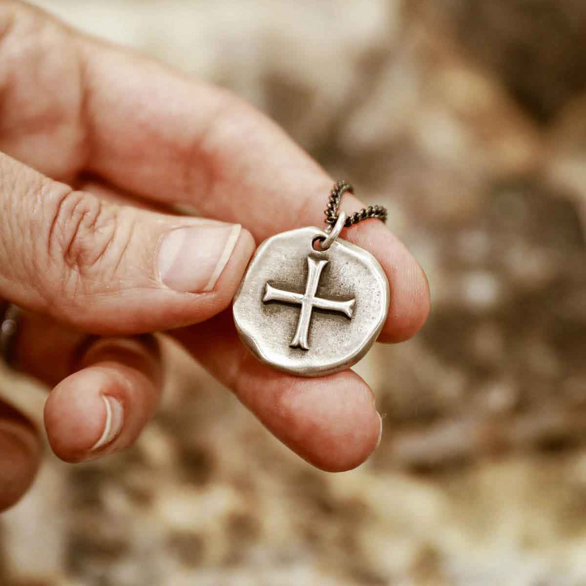 Man wearing Roman Cross Coin necklace handcrafted in sterling silver strung on sterling silver curb chain 