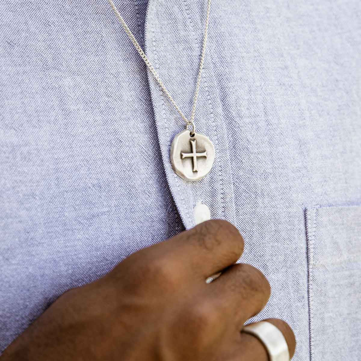 Man wearing Roman Cross Coin necklace handcrafted in sterling silver strung on sterling silver curb chain 