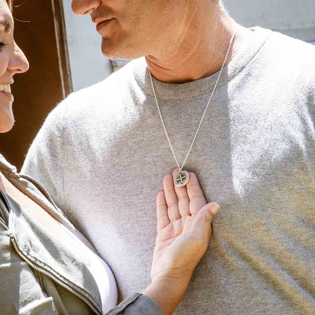 Man wearing Roman Cross Coin necklace handcrafted in sterling silver strung on sterling silver curb chain 