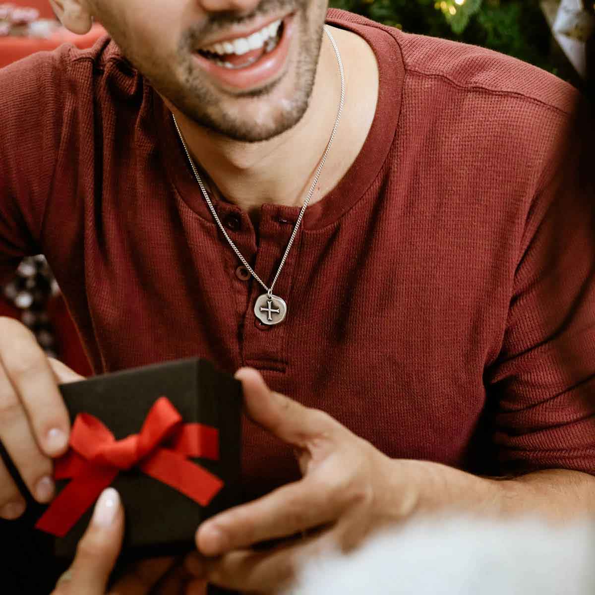 man wearing roman cross coin necklace