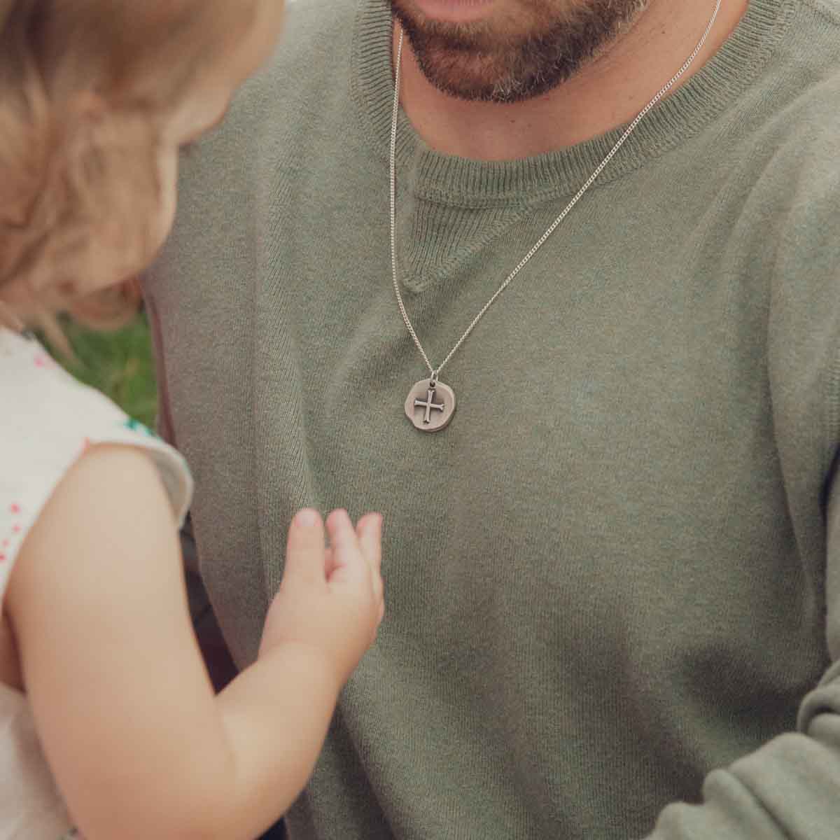 Man wearing Roman Cross Coin necklace handcrafted in sterling silver strung on sterling silver curb chain along with his daughter