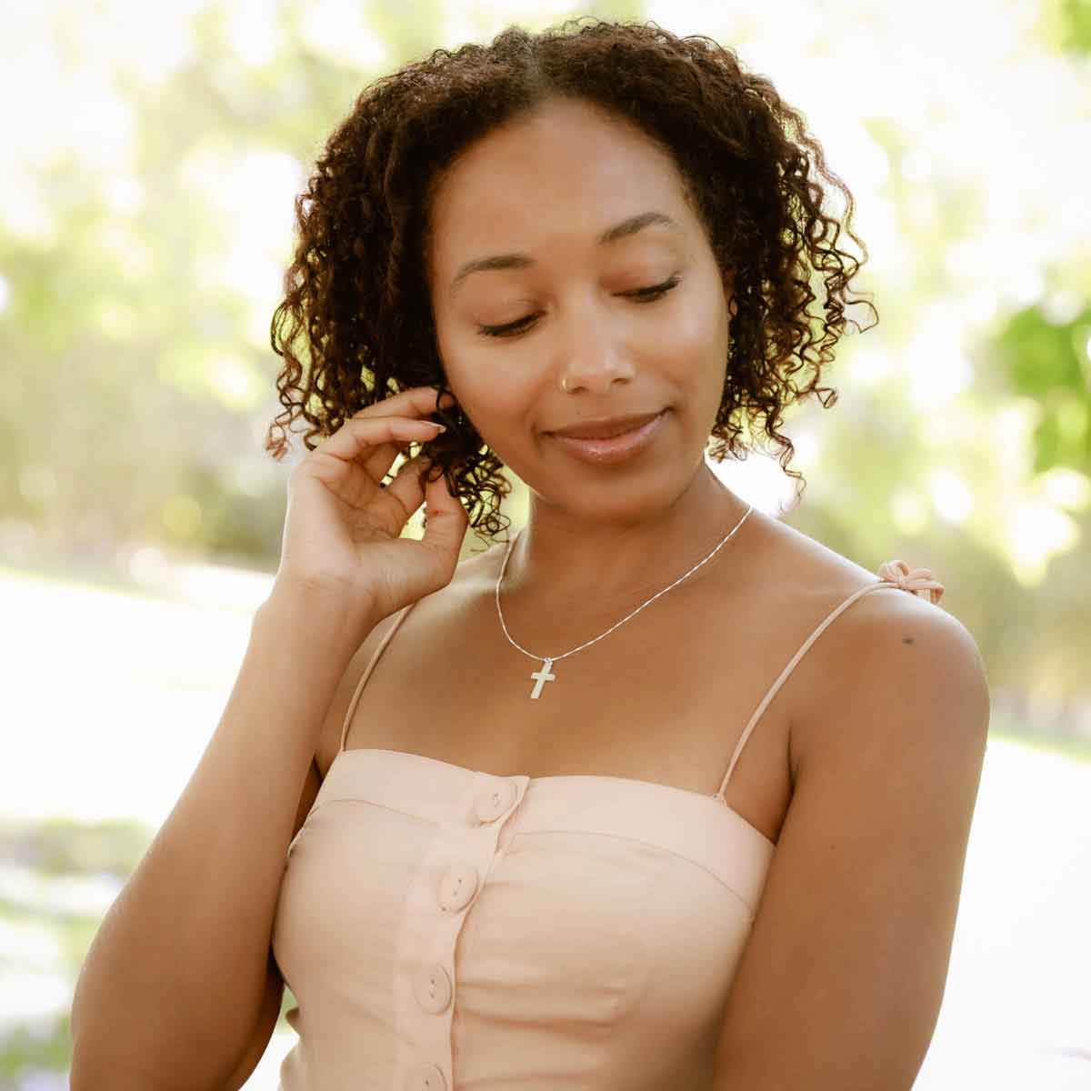 woman holding a sterling silver Rooted and Grounded Cross necklace