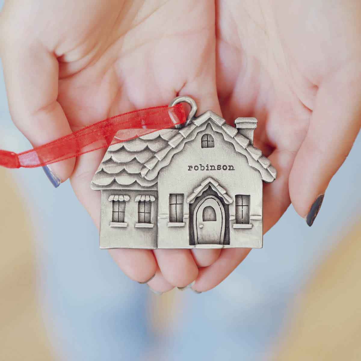 a hand hanging a pewter Safe and Warm Ornament