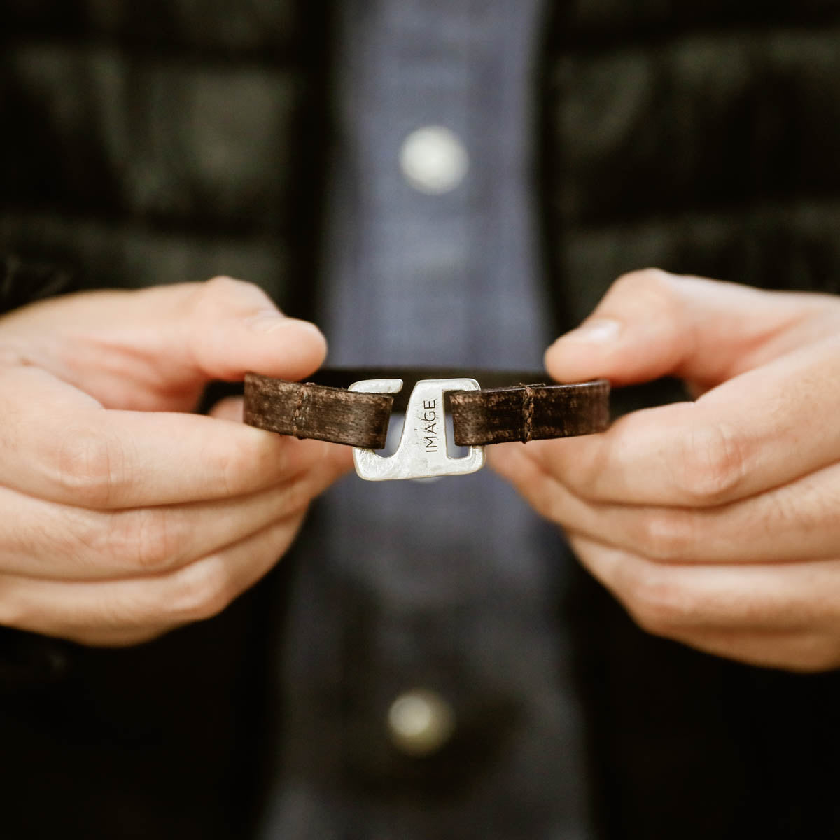 Man wearing Brown Connection bracelet handcrafted with a distressed leather strap and sterling silver closure customizable with a name