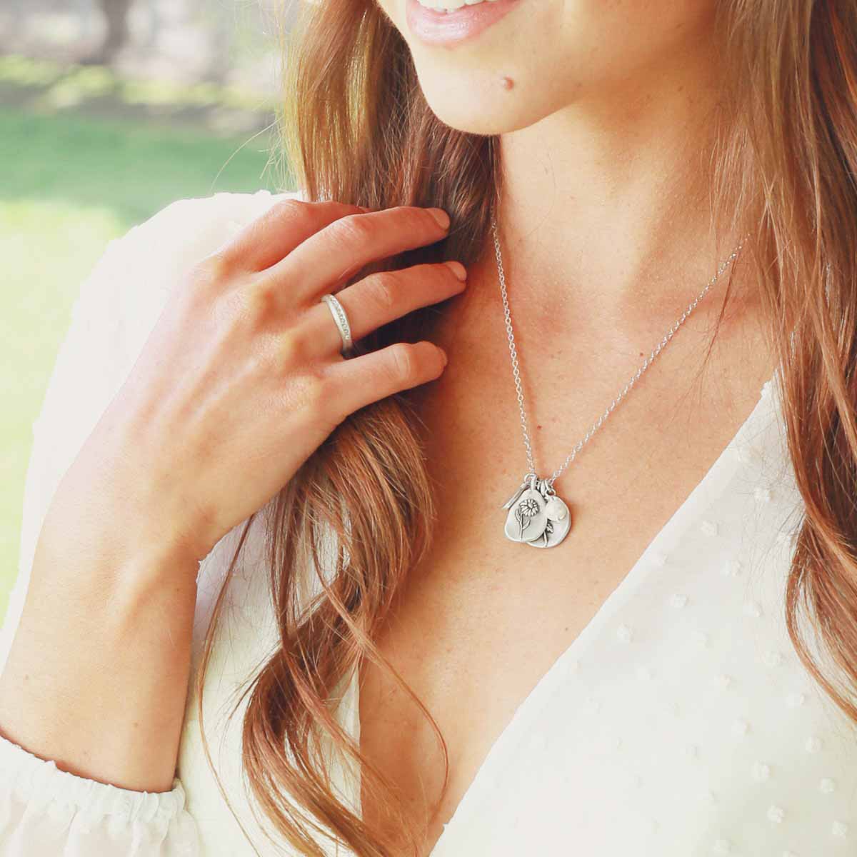 Girl wearing her September birth flower necklace handcrafted in sterling silver with a special birth month charm strung with a vintage freshwater pearl