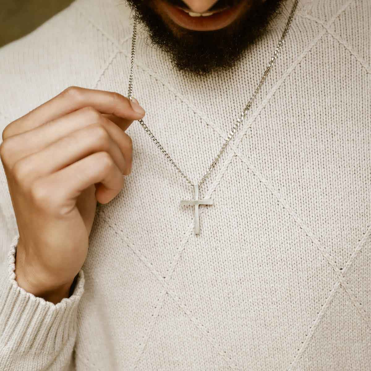 man holding a pewter Set Free Cross Necklace