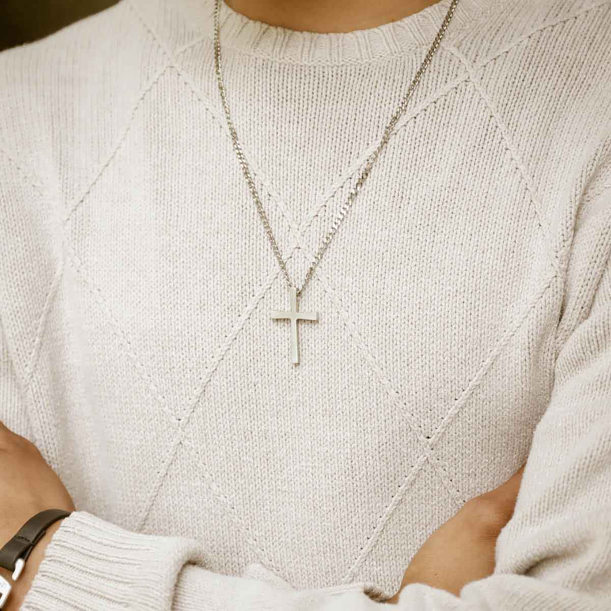 man holding a pewter Set Free Cross Necklace