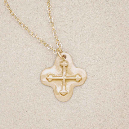 14k yellow gold shining light cross necklace, on beige background