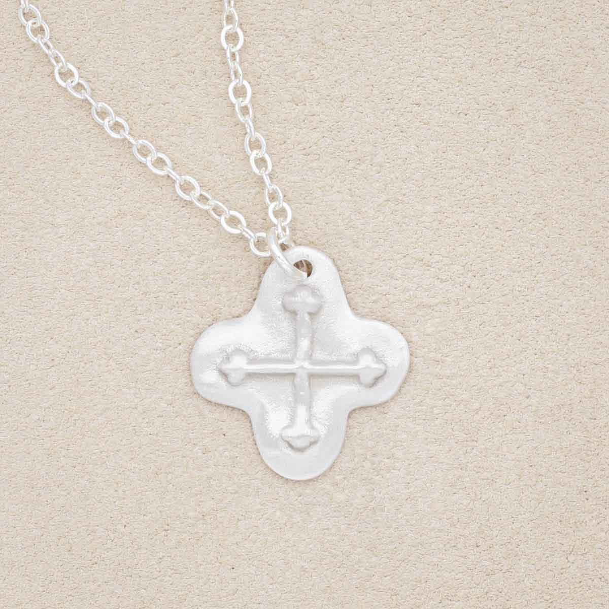 sterling silver shining light cross necklace on beige background