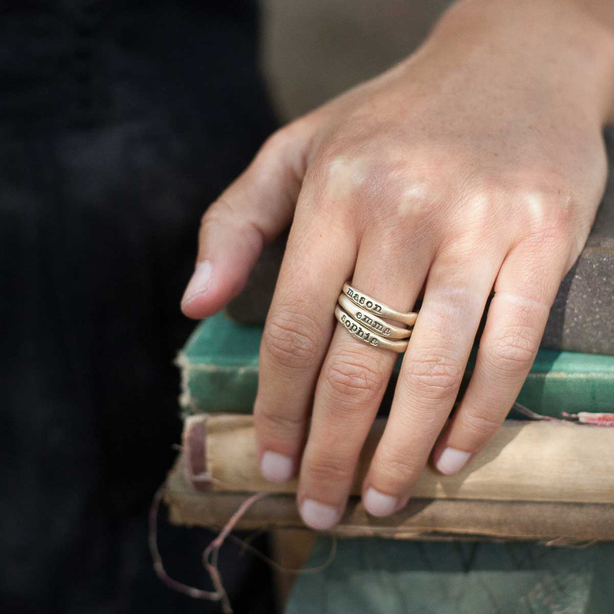 Woman showing her Personalized 10k yellow gold stackable name rings 