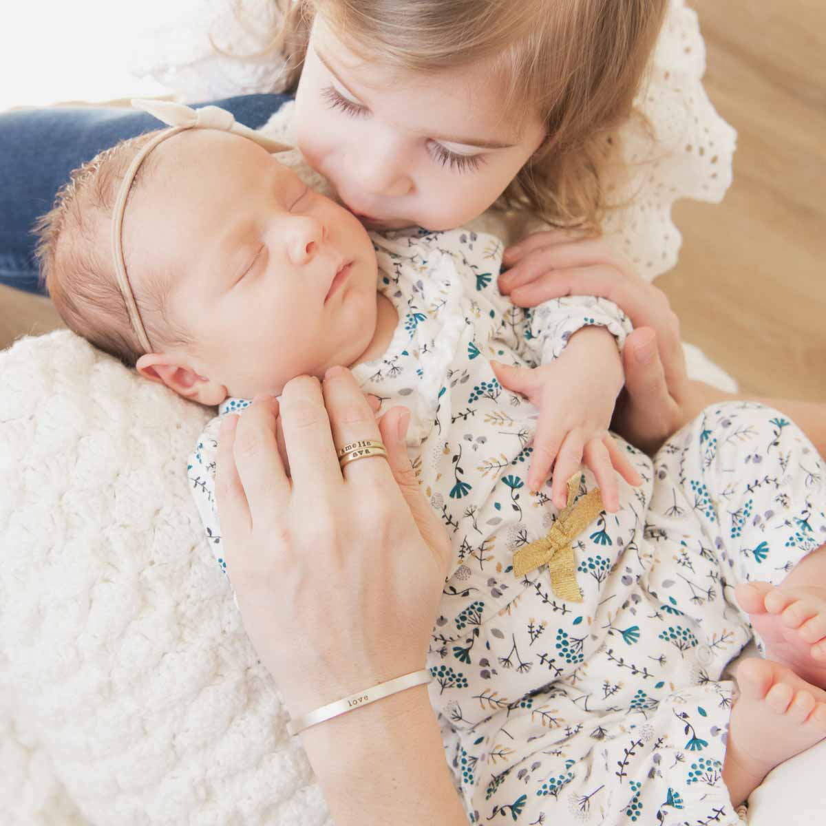 Woman showing her Personalized 10k yellow gold stackable name rings while holding her baby