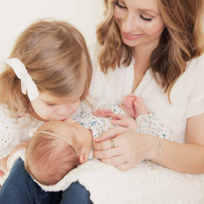 Woman showing her Personalized 10k yellow gold stackable name rings while holding her baby