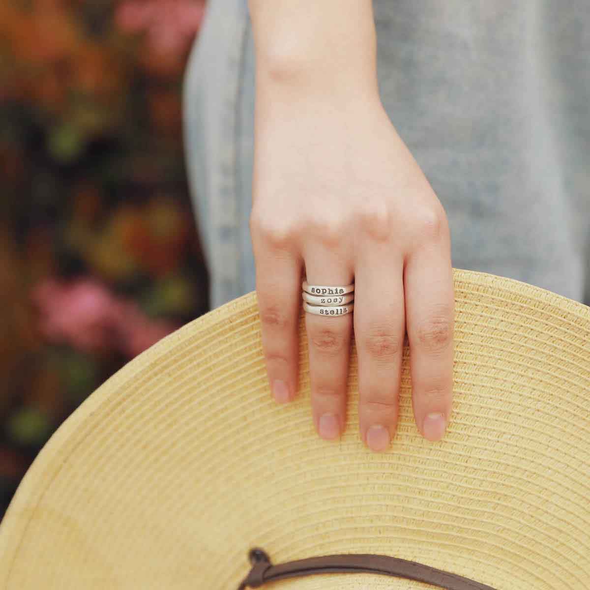 girl wearing personalized sterling silver stackable name ring trio 