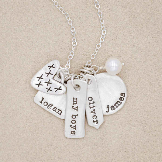 sterling silver storyteller necklace with personalized charms and freshwater pearl on beige background